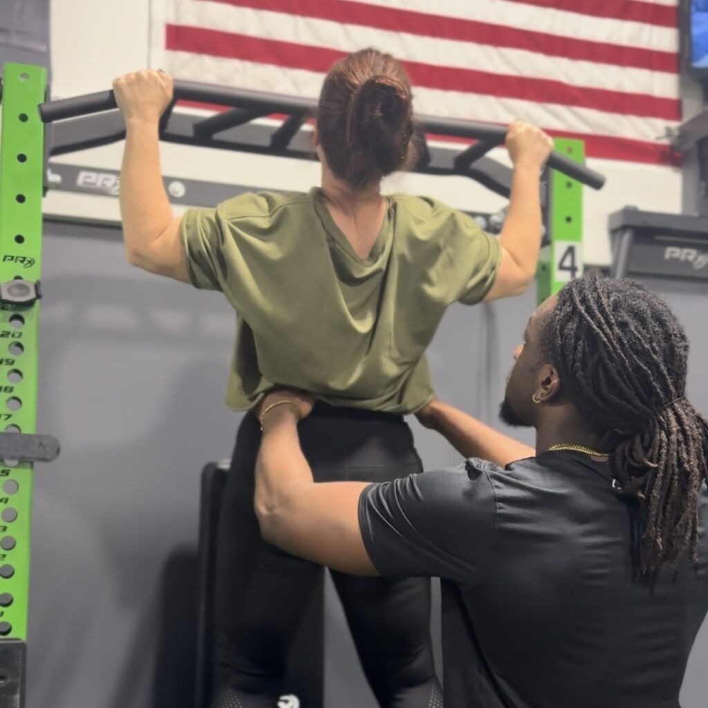 Pull up woman, trainer assisting
